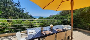 A terrace with a table set for two, a yellow umbrella, and a view of the sea. - House with sea view, private beach access, 6/7 Pers. (Clohars-Carnoët)