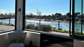 Ein modernes Zimmer mit großen Fenstern mit Blick auf eine Marina und einen Fluss.