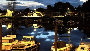 Ein Yachthafen mit vertäuten Booten, ruhigem Wasser und Gebäuden im Hintergrund unter einem bewölkten Himmel.