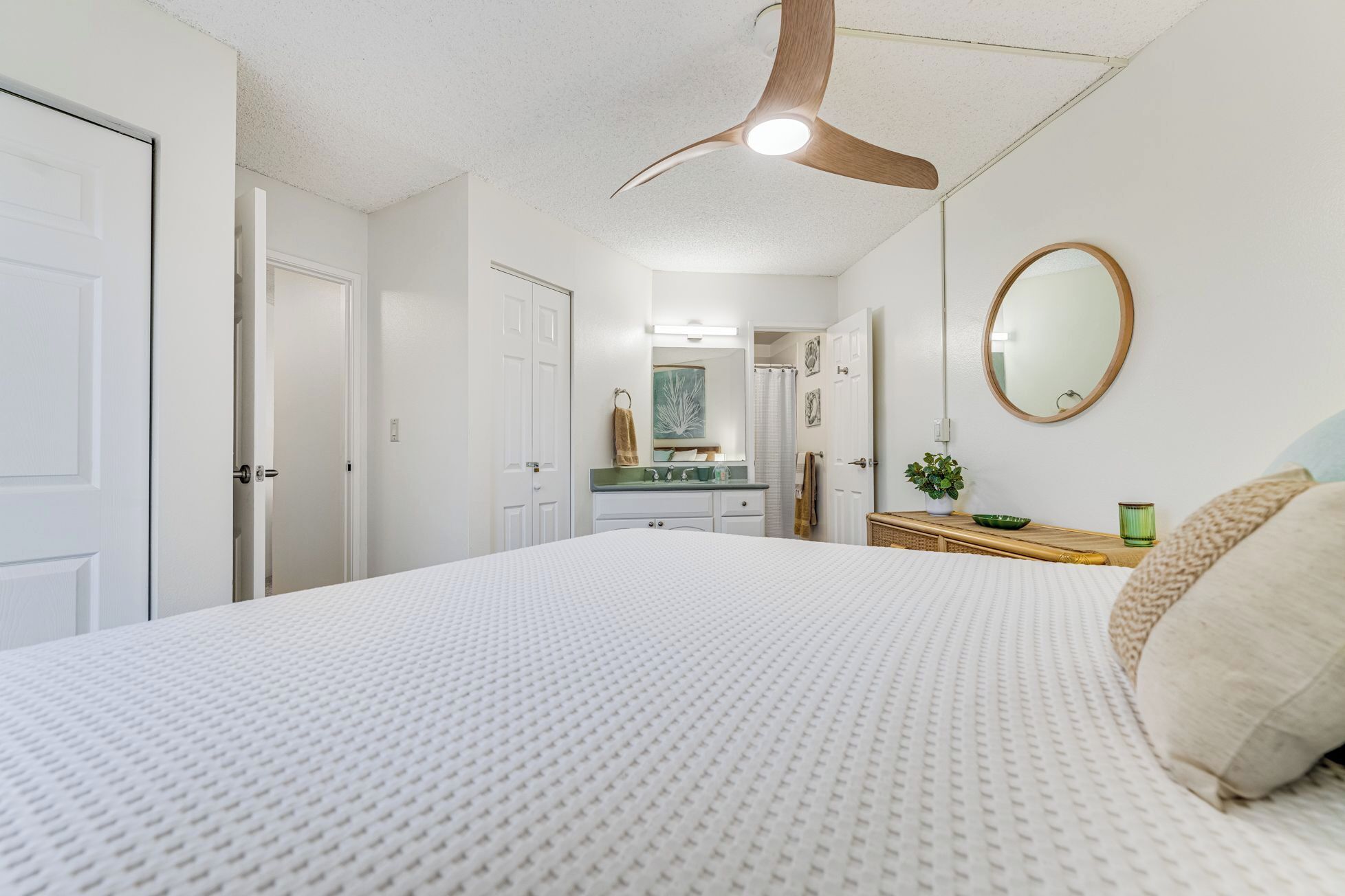 Ein Schlafzimmer mit einem großen Bett, einem Deckenventilator, einem Spiegel und einer Kommode.
