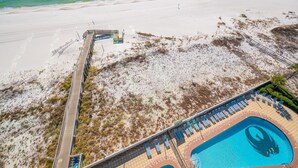 Ein Luftbild eines Strandresorts mit Schwimmbad, Zugang zum Strand und einer Promenade.
