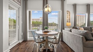 A dining area with a round table, chairs, and a chandelier. - Wraparound Balcony ~ Coastal Luxury Condo (Miramar Beach)