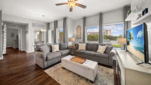 A modern living room with two grey sofas, a wooden coffee table, and a ceiling fan. - Wraparound Balcony ~ Coastal Luxury Condo (Miramar Beach)