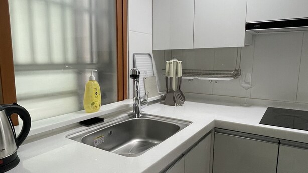A modern kitchen with white cabinets, a stainless steel sink, and a window with blinds. - Cozy 1-bedroom apartment with AC, WiFi in lovely Seoul (Seoul)