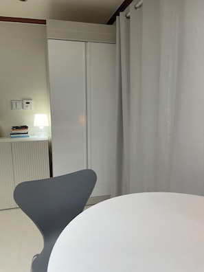 A room with a white table, a grey chair, a radiator, a lamp, and a wardrobe. - Cozy 1-bedroom apartment with AC, WiFi in lovely Seoul (Seoul)