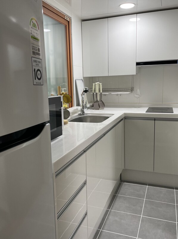 A modern kitchen with white cabinets, a stainless steel sink, and a built-in oven.