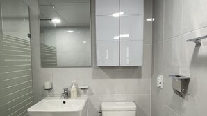 A modern bathroom with a white sink, toilet, and cabinet. - Cozy 1-bedroom apartment with AC, WiFi in lovely Seoul (Seoul)