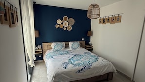 A bedroom with a bed, a woven headboard, a wall-mounted light fixture, and a woven rug. - Superb villa with pool 10 minutes from the beach (Sérignan)