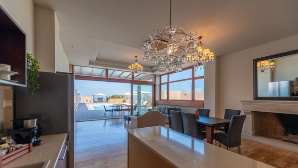 A modern kitchen with a central island, large windows, and a chandelier. - Luxury Villa Suzana - Three Bedroom Villa, Sleeps 6 (Chersonisos)