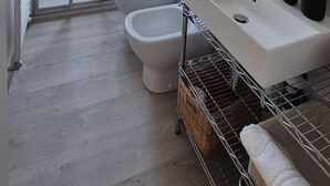 Un bagno moderno con box doccia in vetro, un lavandino bianco e un water.