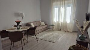 Un soggiorno moderno con angolo da pranzo, un divano, un tavolino da caffè e una TV su un mobile.