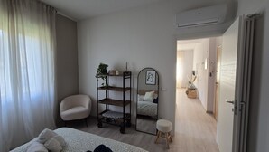 Una camera da letto moderna con un letto, una sedia, un comodino, uno specchio e una mensola con piante.
