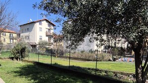 Un quartiere residenziale con un prato, una recinzione in metallo e un edificio con tetto rosso.
