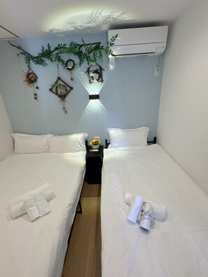 Two single beds with white linens and pillows, each with a nightstand and a remote control.