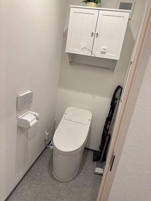Bathroom features a toilet, storage cabinet, and paper towel dispenser.