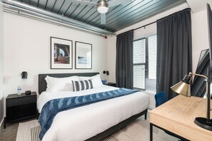 Relax in a spacious room with a large bed, desk, and ceiling fan.