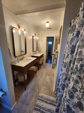 Un baño con dos lavamanos, un espejo grande y una cortina de ducha con estampado floral.