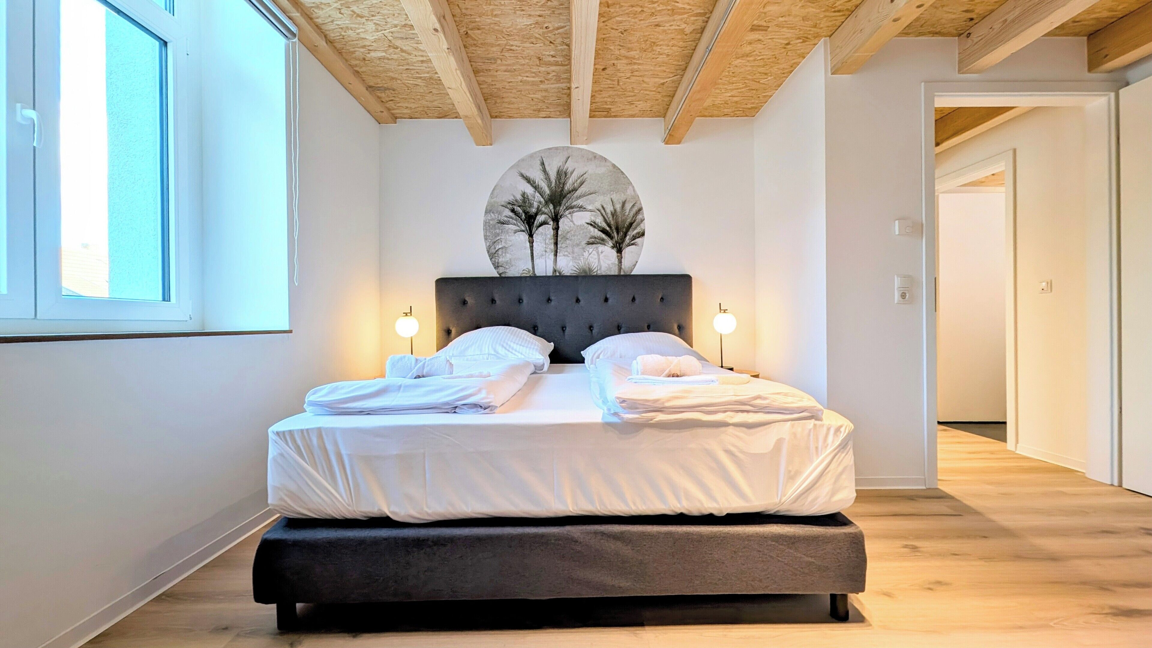 A double bed with a dark headboard, two bedside lamps, and a circular wall decoration above.