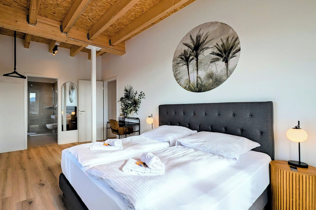A bedroom with a bed, bedside table, and a wall-mounted artwork.