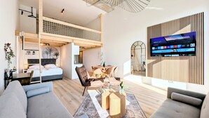 Een moderne woonkamer met een vide, een televisie bevestigd aan een houten paneelwand, en een eetgedeelte met een tafel en stoelen.