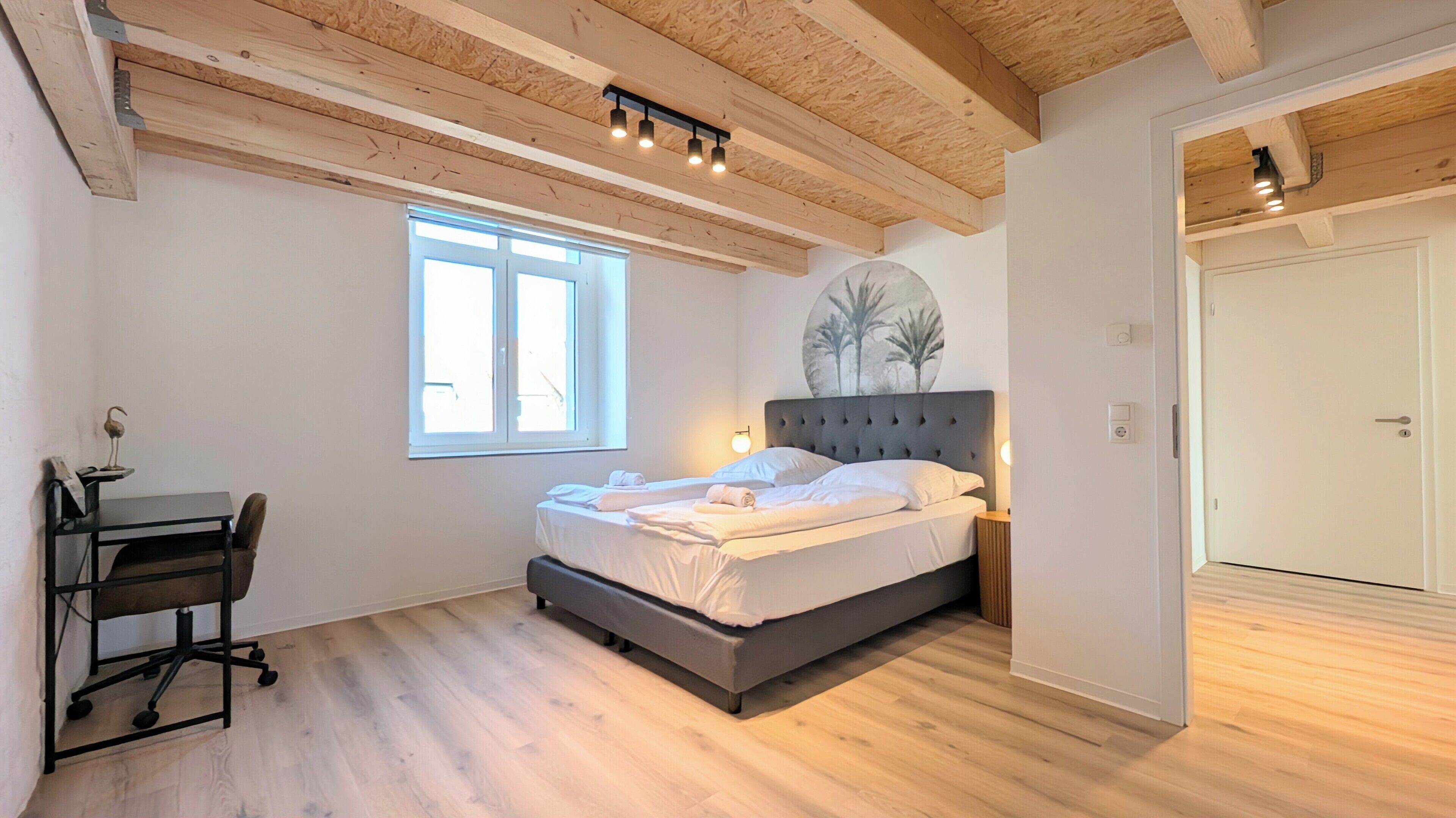 Un dormitorio con una cama, un escritorio y una ventana.