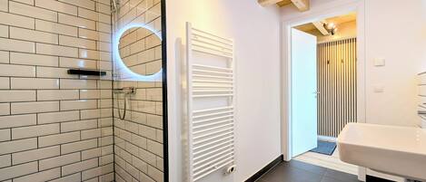 A modern bathroom with a shower, a toilet, and a sink.