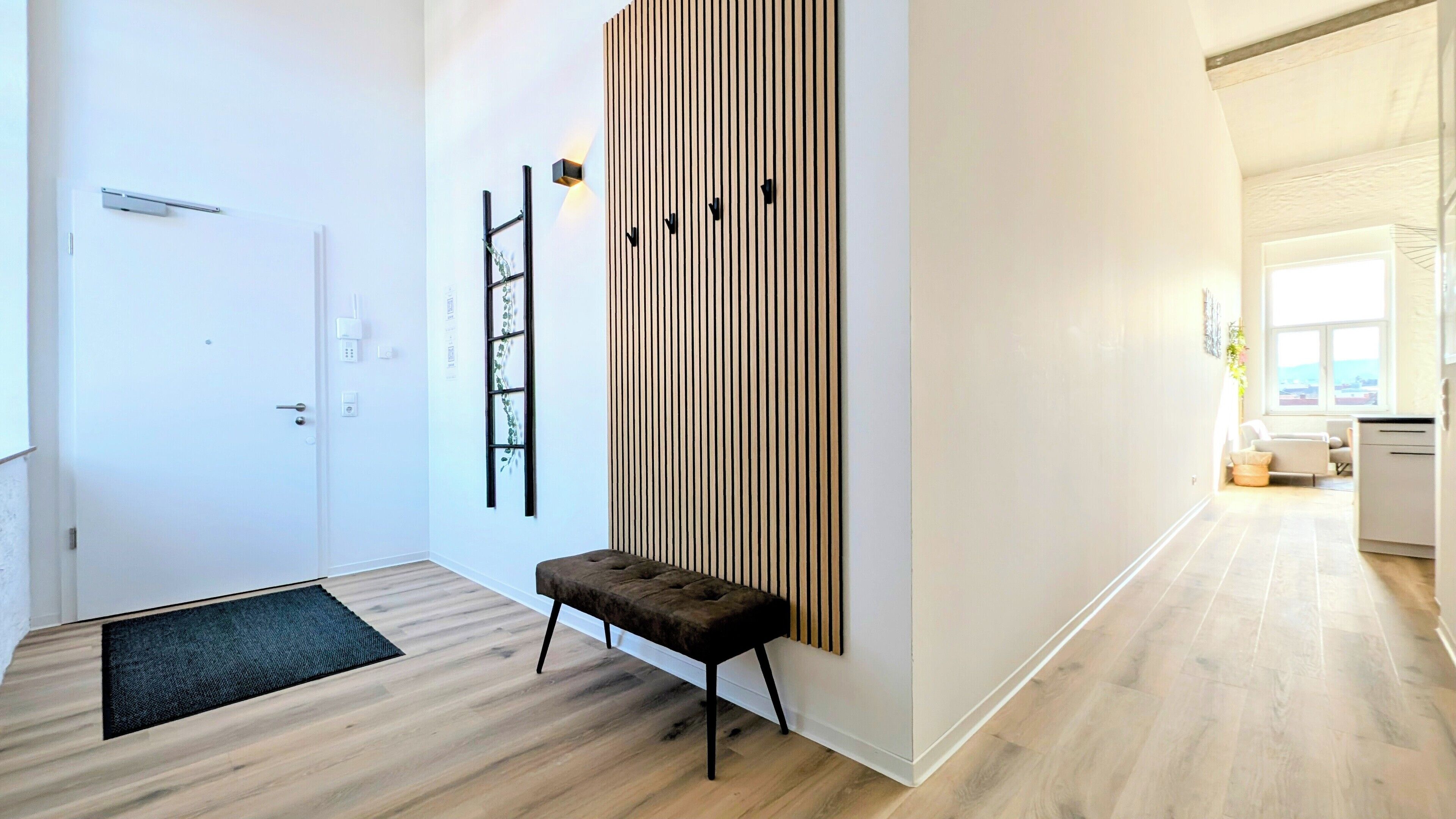 Un couloir moderne avec un banc, un mur en lambris de bois et une porte.