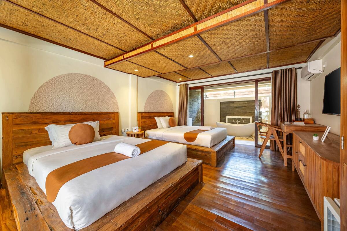 Une chambre d’hôtel avec deux lits, un plancher en bois, un bureau et une grande fenêtre.