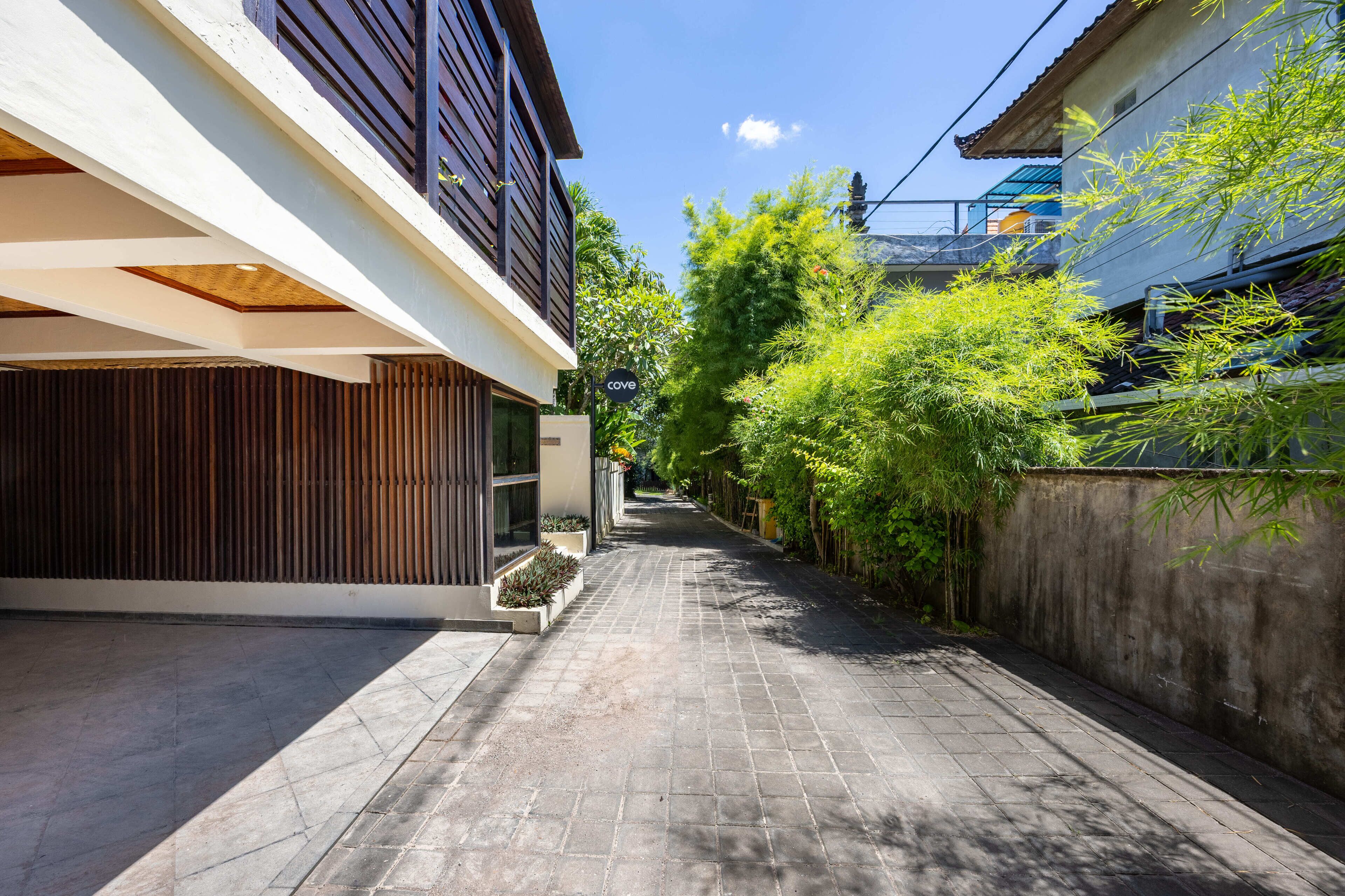 A narrow, paved alleyway flanked by modern buildings with large windows and wooden slats.