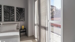 A bedroom with a bed, a nightstand with a lamp, and a balcony with a railing. - Italianway Comfort - Copernico 47 B (Milan)