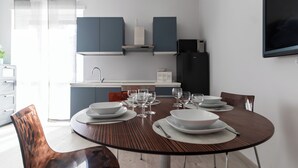 A modern kitchen with grey cabinets, a built-in stove, and a black refrigerator. - Italianway Comfort - Copernico 47 B (Milan)