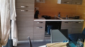Une cuisine compacte avec des meubles en bois, un lave-vaisselle encastré et un petit coin repas comprenant une table et des chaises.