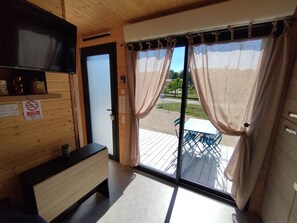 Ein Zimmer mit Holzvertäfelung, einer Schiebetür aus Glas zum Außenbereich mit Tisch und Stühlen sowie einem an der Wand befestigten Fernseher.