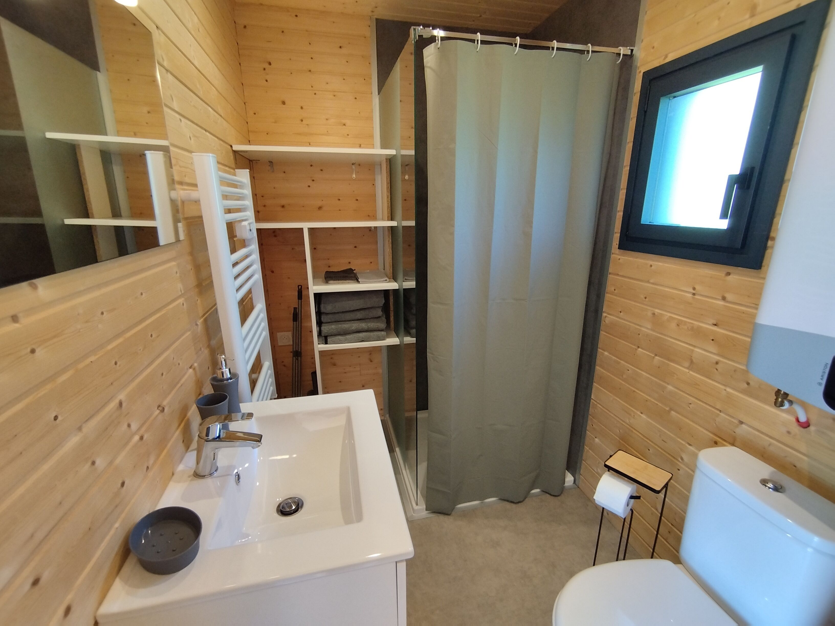 A wooden interior bathroom with a sink, toilet, and shower curtain.