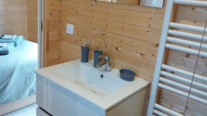 Une salle de bain moderne avec un intérieur en bois, un lavabo blanc, un miroir et un porte-serviettes.