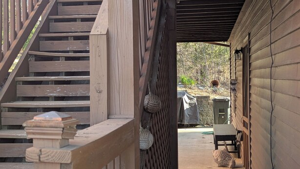A wooden staircase leading to a covered porch area with a bench and a trash can. - Haffa's Unrivaled Expeditions At Lake Murray Palmetto Retreat (Gilbert)