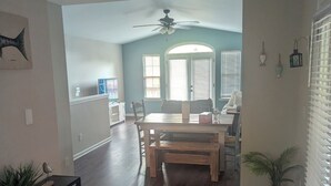 A spacious living area with a dining table, wooden flooring, and a ceiling fan. - Haffa's Unrivaled Expeditions At Lake Murray Palmetto Retreat (Gilbert)