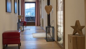 A spacious hallway with a red bench, a white rug, and a wooden star decoration. - Apartment in Seefeld Near Ski Slopes (Seefeld in Tirol)