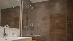A modern bathroom with a large mirror, a wooden vanity, a shower area, and a towel on the floor. - Apartment in Seefeld Near Ski Slopes (Seefeld in Tirol)