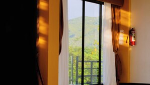 A room with a large window, curtains, and a fire extinguisher on the wall. - Sacaan Tropical Breeze Resort (Sogod)