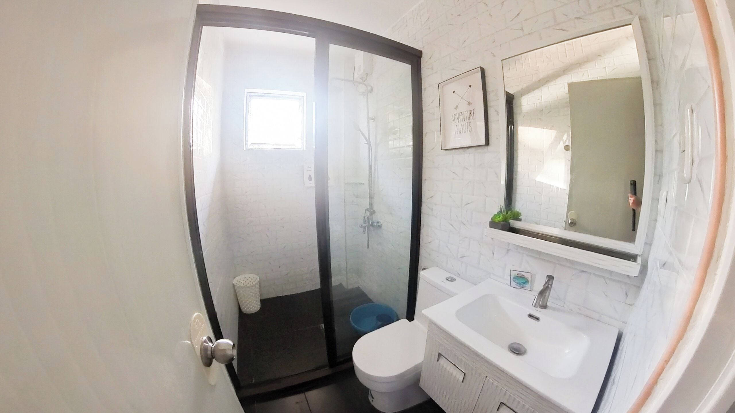 A bathroom with a glass shower enclosure, a white sink, and a toilet.