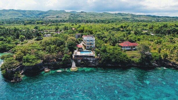 An aerial view of a coastal property with a swimming pool, multiple buildings, and lush greenery. - Sacaan Tropical Breeze Resort (Sogod)