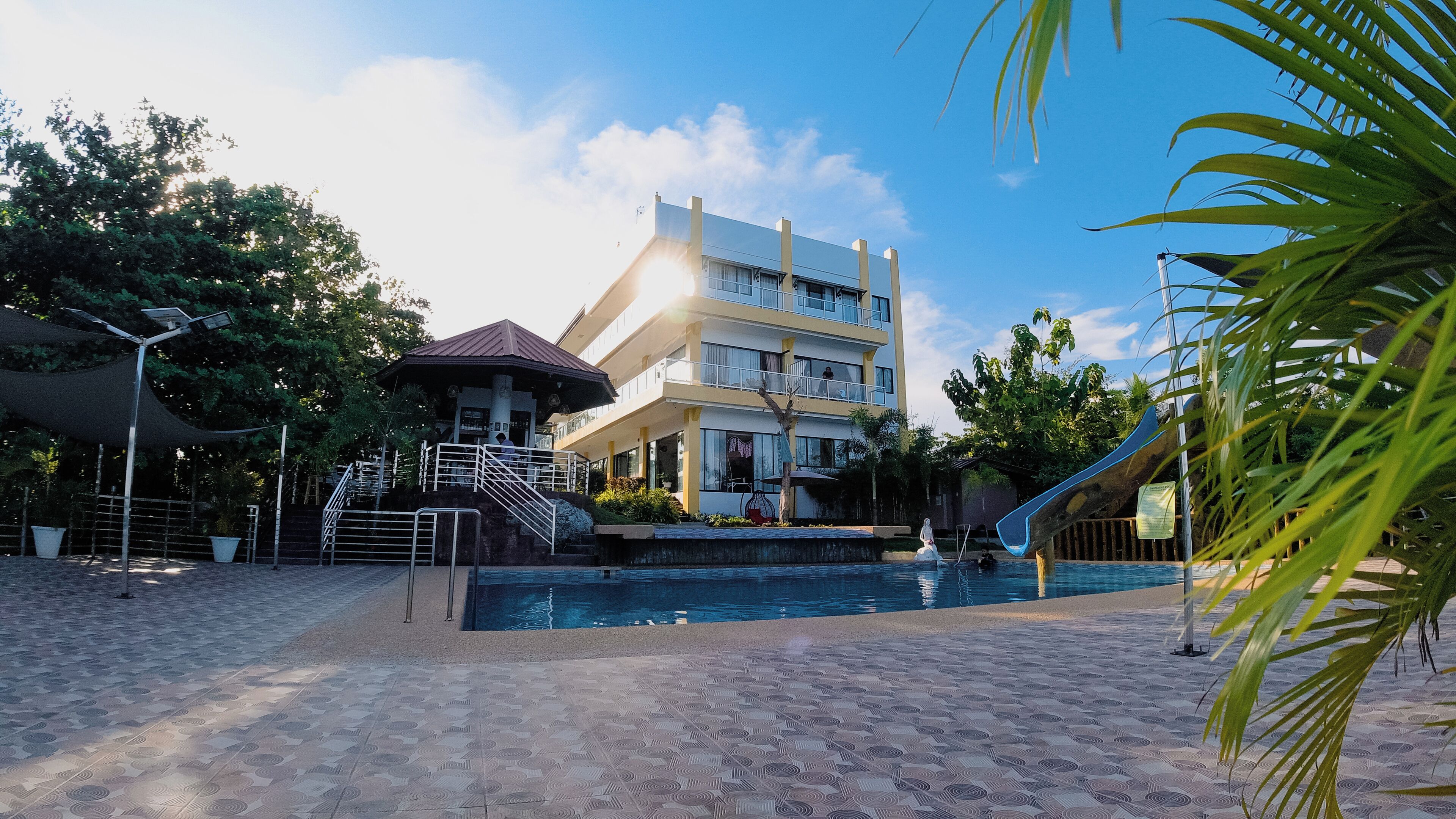 A hotel with a pool, a covered area, and a staircase leading to the upper floors.