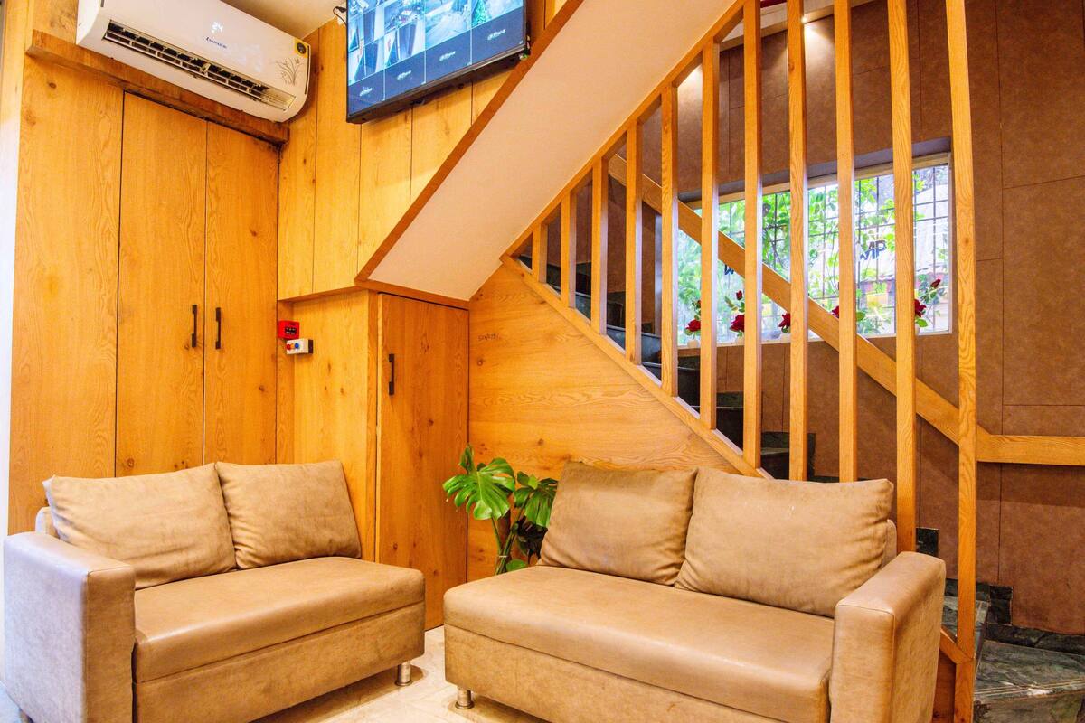 Ein gemütlicher Raum mit zwei beigen Sofas, einer Holztreppe und einem an der Wand befestigten Fernseher.