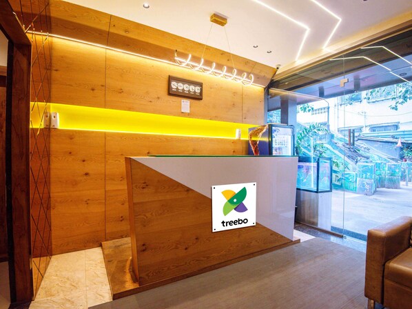 A reception desk with a wooden finish and a glass partition, featuring a logo and a sign with Japanese characters.