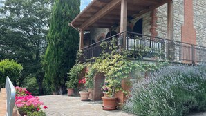 A stone building with a wooden balcony, potted plants, and a stone-paved courtyard.