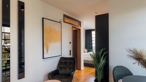 A modern living room with a dark armchair, a round table, and a large abstract painting. - Urban Heaven Aparthotel (Hamburg)