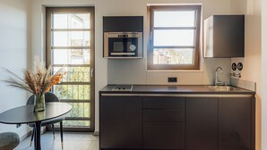 A compact kitchen with a built-in oven, a sink, and a window providing natural light. - Urban Heaven Aparthotel (Hamburg)