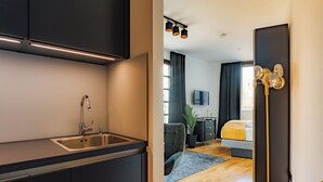 A modern kitchen with a sink and cabinets, a dining area with a table and chairs, and a bedroom with a bed and a TV. - Urban Heaven Aparthotel (Hamburg)