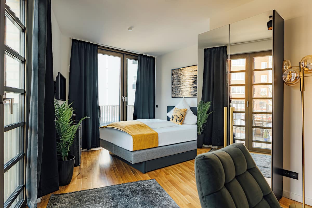 Ein modernes Schlafzimmer mit Bett, großem Fenster und Blick auf die Stadt.